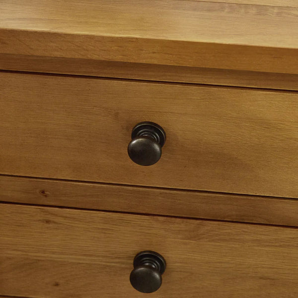 Close-up of a wooden drawer with black knobs