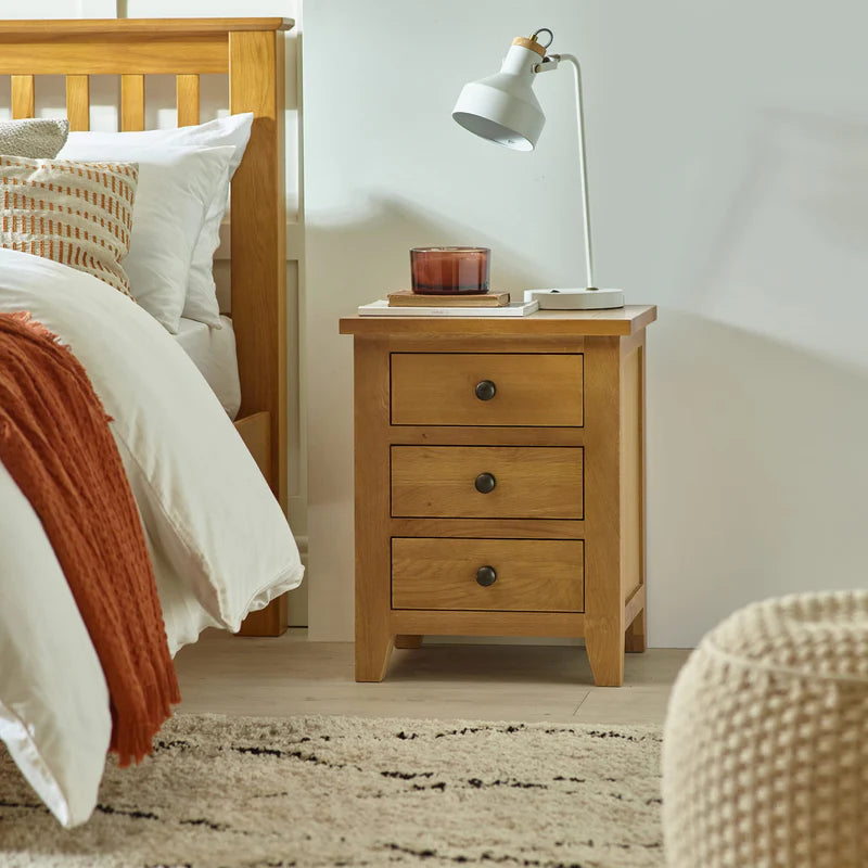 Wooden nightstand with three drawers on a white background