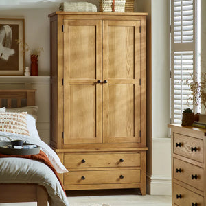 Wooden wardrobe with two doors and two drawers in a bedroom setting.