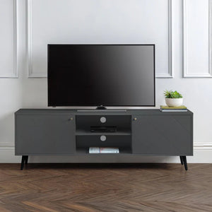 Gray TV stand with a television and decorative items in a room with white walls and wooden flooring.
