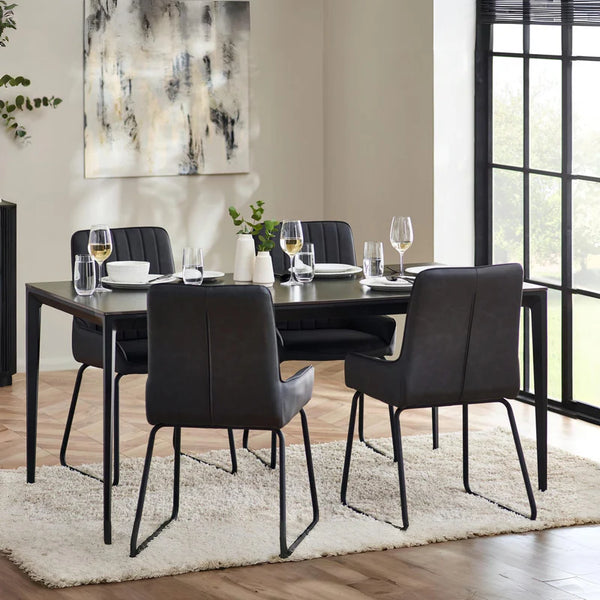 Dining room with a black table and chairs on a white rug, with a large window in the background.