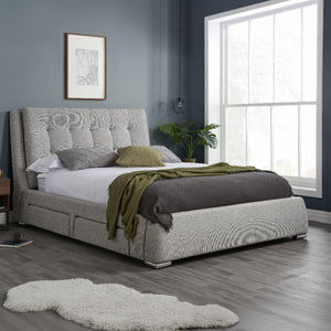 Gray upholstered bed with green blanket in a bedroom setting