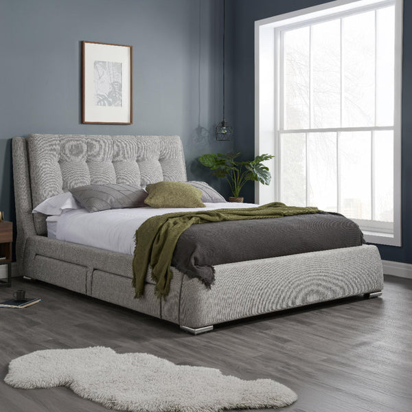 Gray upholstered bed with green blanket in a bedroom setting