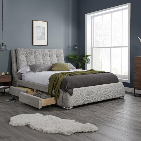 Gray upholstered bed with storage drawers in a bedroom setting.