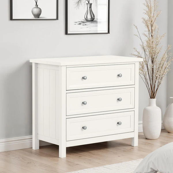 White dresser with three drawers in a room with framed pictures and decorative vases.