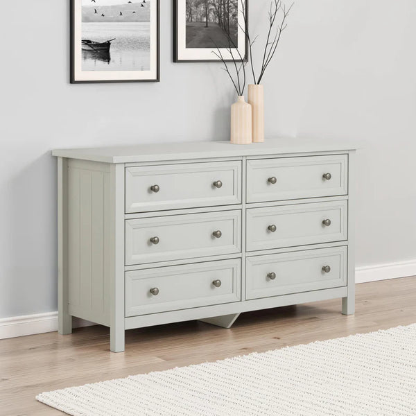 Light gray dresser with six drawers in a room with framed pictures on the wall.