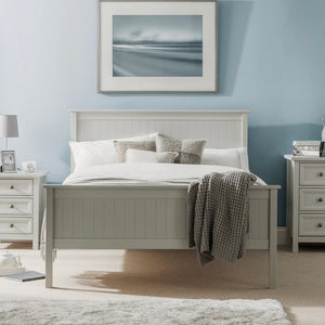 Neatly made bed in a bedroom with light blue walls, nightstands, and a framed picture.