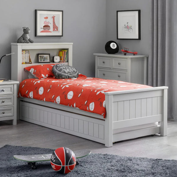 Children's bedroom with a white bed, red bedding, and various toys.
