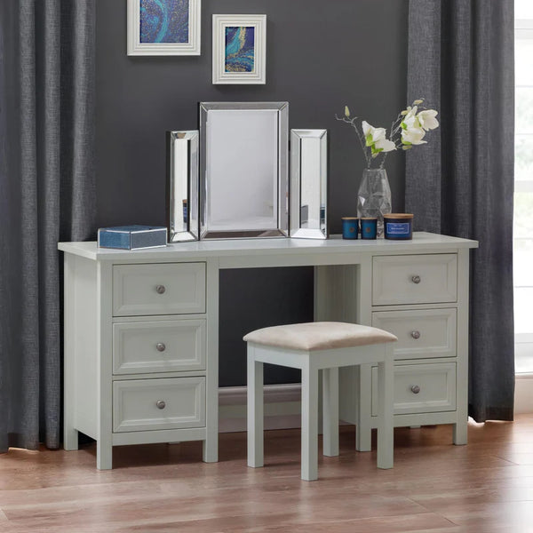White dressing table with mirror, stool, and decorative items against a dark gray wall.