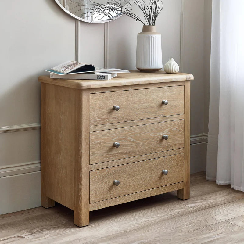 Wooden dresser with three drawers and metallic handles on a white background