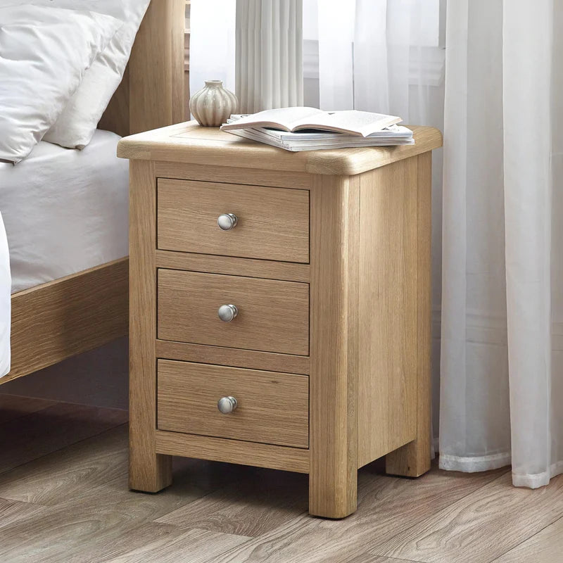 Wooden nightstand with three drawers and silver knobs on a white background