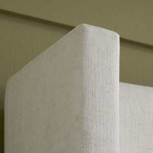 Close-up of a textured white headboard against a green wall.