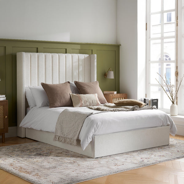Neatly made bed with decorative pillows in a bright bedroom setting