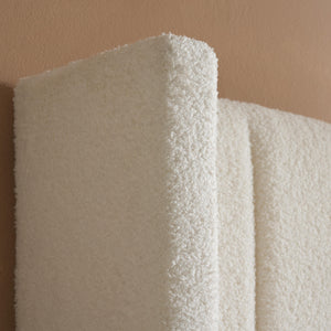 Close-up of a textured white fabric roll against a beige background