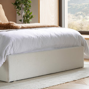 Bed with white bedding in a room with a window and plant