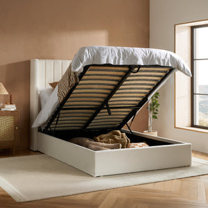 White upholstered bed with open storage compartment in a room with a window and wooden floor.
