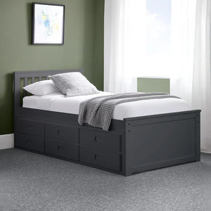 Black bed frame with storage drawers in a room with green walls and white curtains.