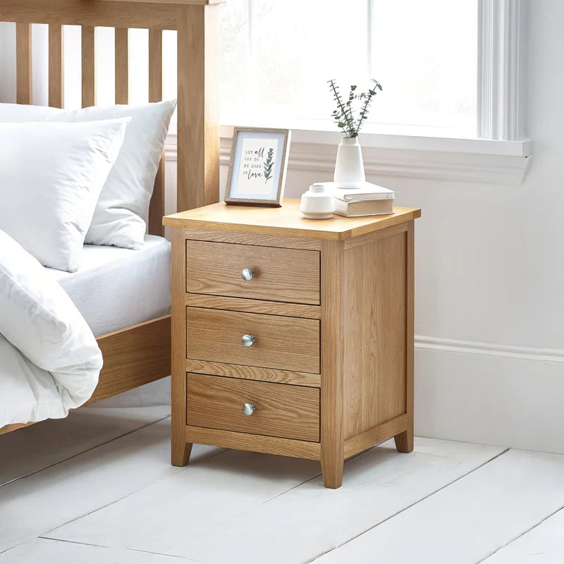 Wooden nightstand with three drawers on a white background