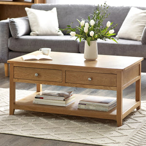 Wooden coffee table with a vase of flowers, books, and a cup in a living room setting.