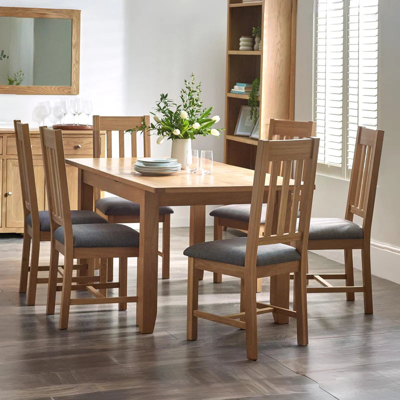 Two wooden chairs with gray cushioned seats on a white background