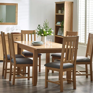 Dining room with wooden table and chairs, bookshelf, and decorative items.