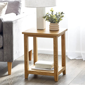 Wooden side table with a lamp, books, and plant in a living room setting.