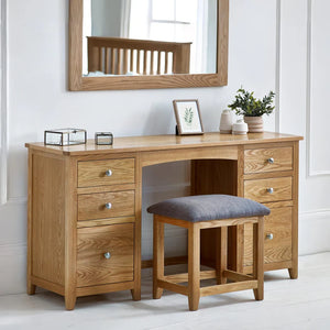 Wooden dressing table with mirror, stool, and decorative items in a room.