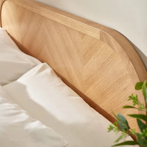 Wooden headboard with white pillows and a plant in a room setting