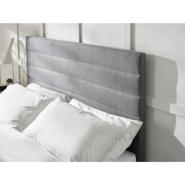 Gray upholstered headboard with white pillows on a bed in a bedroom setting.