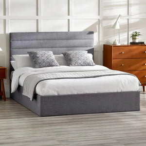 Gray upholstered bed with white bedding in a bedroom setting.