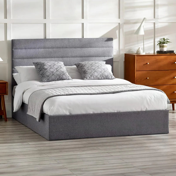 Gray upholstered bed with white bedding in a bedroom setting.