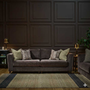 Gray sofa with patterned cushions in a room with dark paneled walls and a rug.