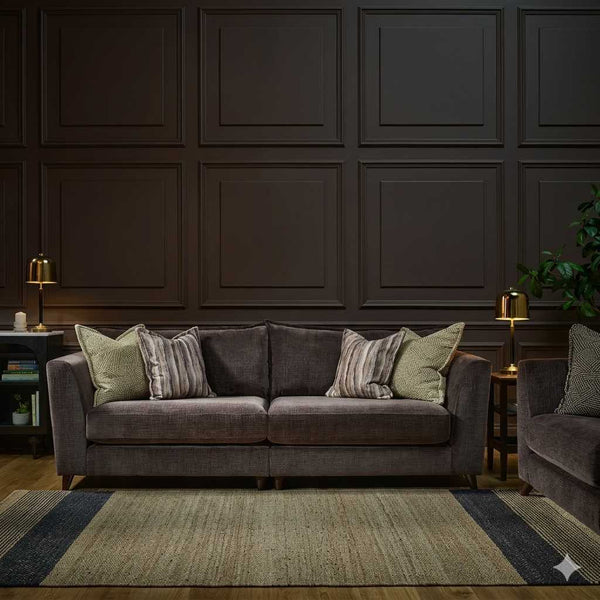 Gray sofa with patterned cushions in a room with dark paneled walls and a rug.