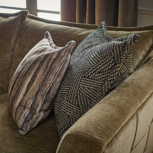 Brown sofa with patterned cushions in a room with curtains.