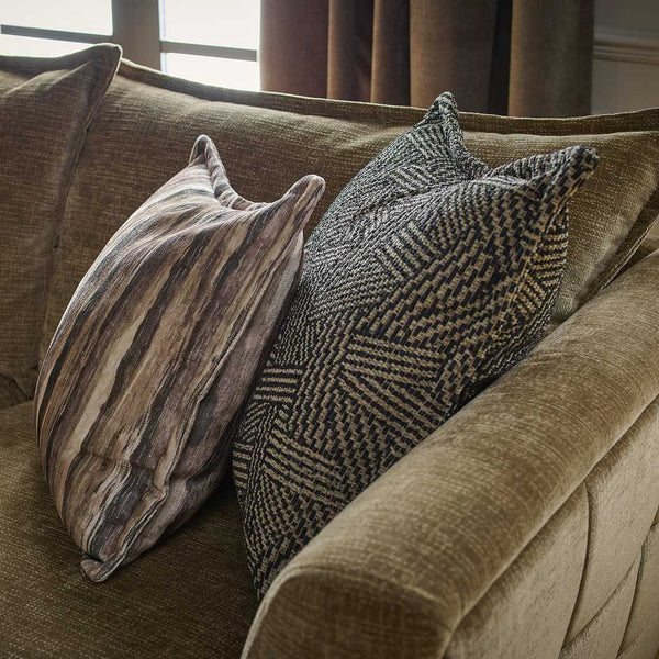 Brown sofa with patterned cushions in a room with curtains.
