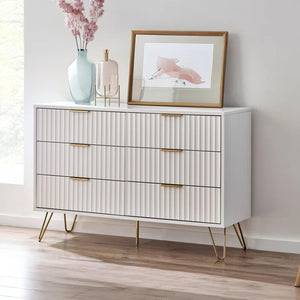 White dresser with gold legs and handles in a room setting with decor items.