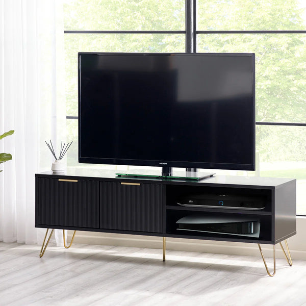 Modern TV stand with a television on top in a bright room with large windows.