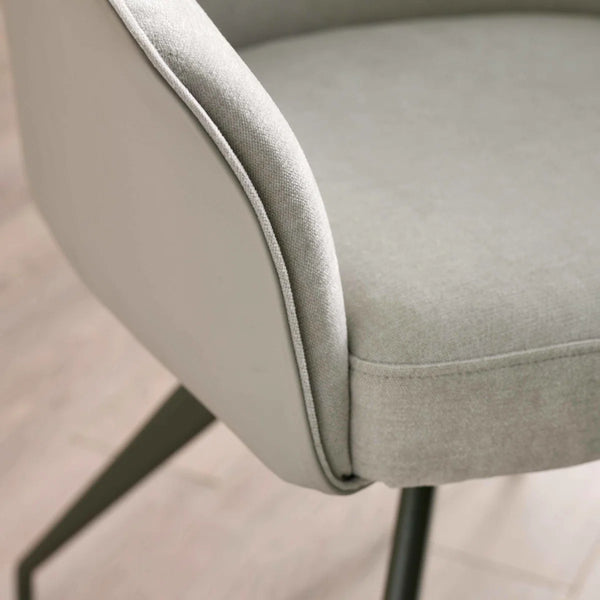 CLOSE UP ON ARM OF A DINING CHAIR WITH BLACK METAL LEGS AND A BLURRED BACKGROUND