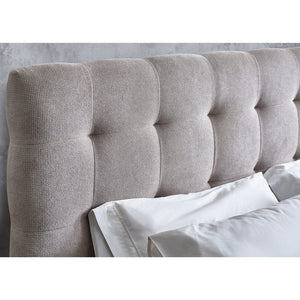 Gray upholstered headboard with tufted design against a light gray wall.