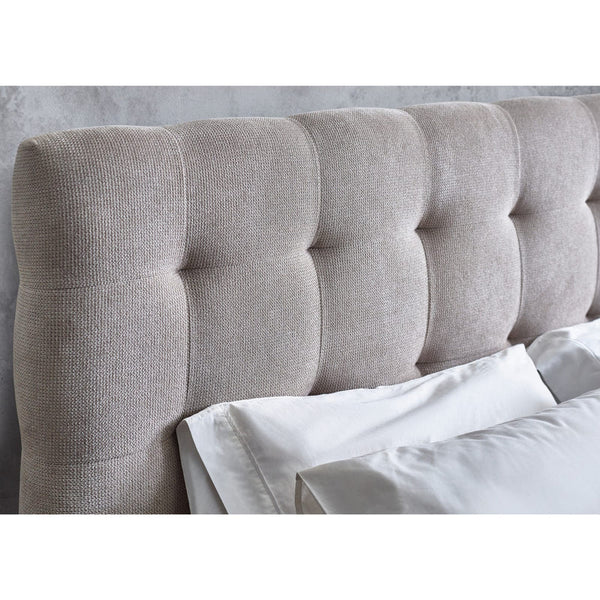 Gray upholstered headboard with tufted design against a light gray wall.