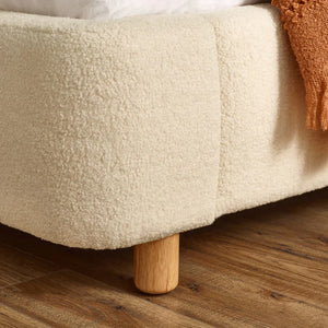 Cream boucle bed frame showing the foot end detail with wooden leg