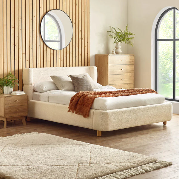 cream bed frame in a modern bedroom with slatted wall behind