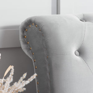 Gray upholstered bed with buttoned details and gold nailhead trim.