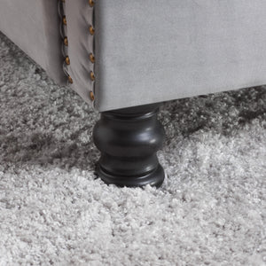 Close-up of a gray upholstered bed leg on a carpeted floor