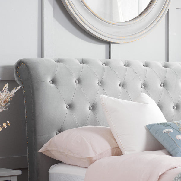 Gray tufted headboard with pillows and a mirror on a light blue wall.