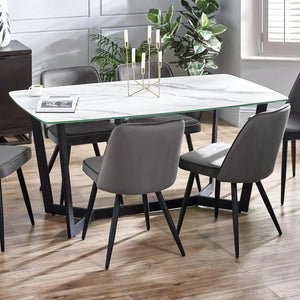 Dining room with a glass table and gray chairs on a wooden floor.