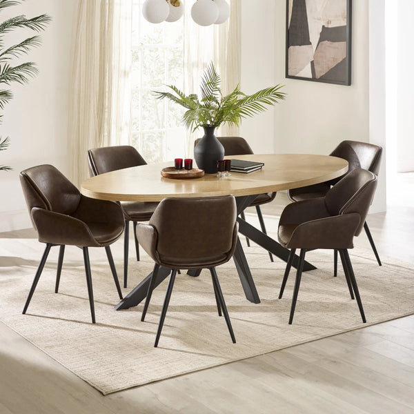 Dining room with a round wooden table and six brown chairs on a light wood floor.