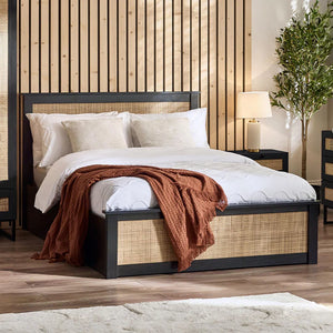 Bedroom with a bed featuring white bedding and a brown blanket, against a wooden paneled wall.