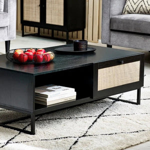Black coffee table with decorative items in a living room setting