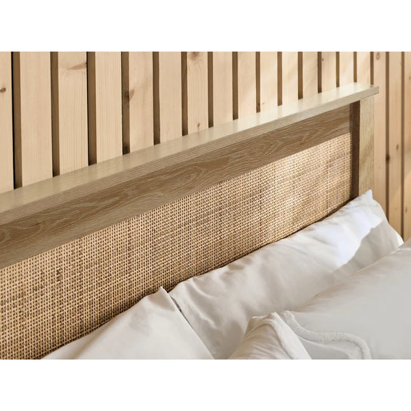 Wooden headboard with wicker detailing against a wooden wall.